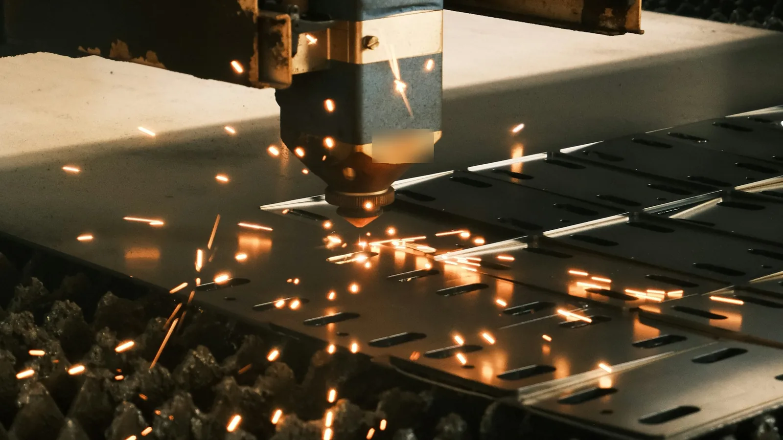 Laser cutter cutting a steel sheet, with sparks flying from the cutting head